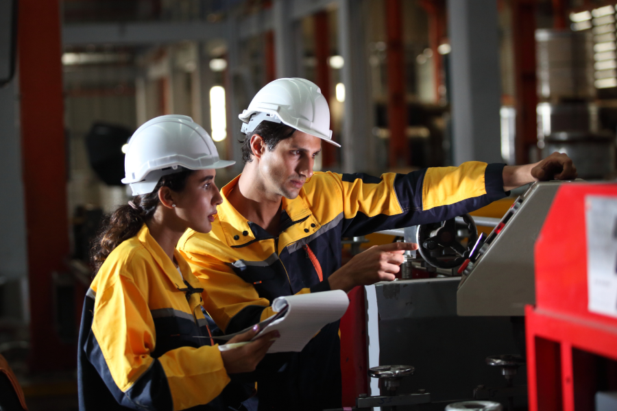 Two mining staff discussing on how to operate the machine in the site workshop.